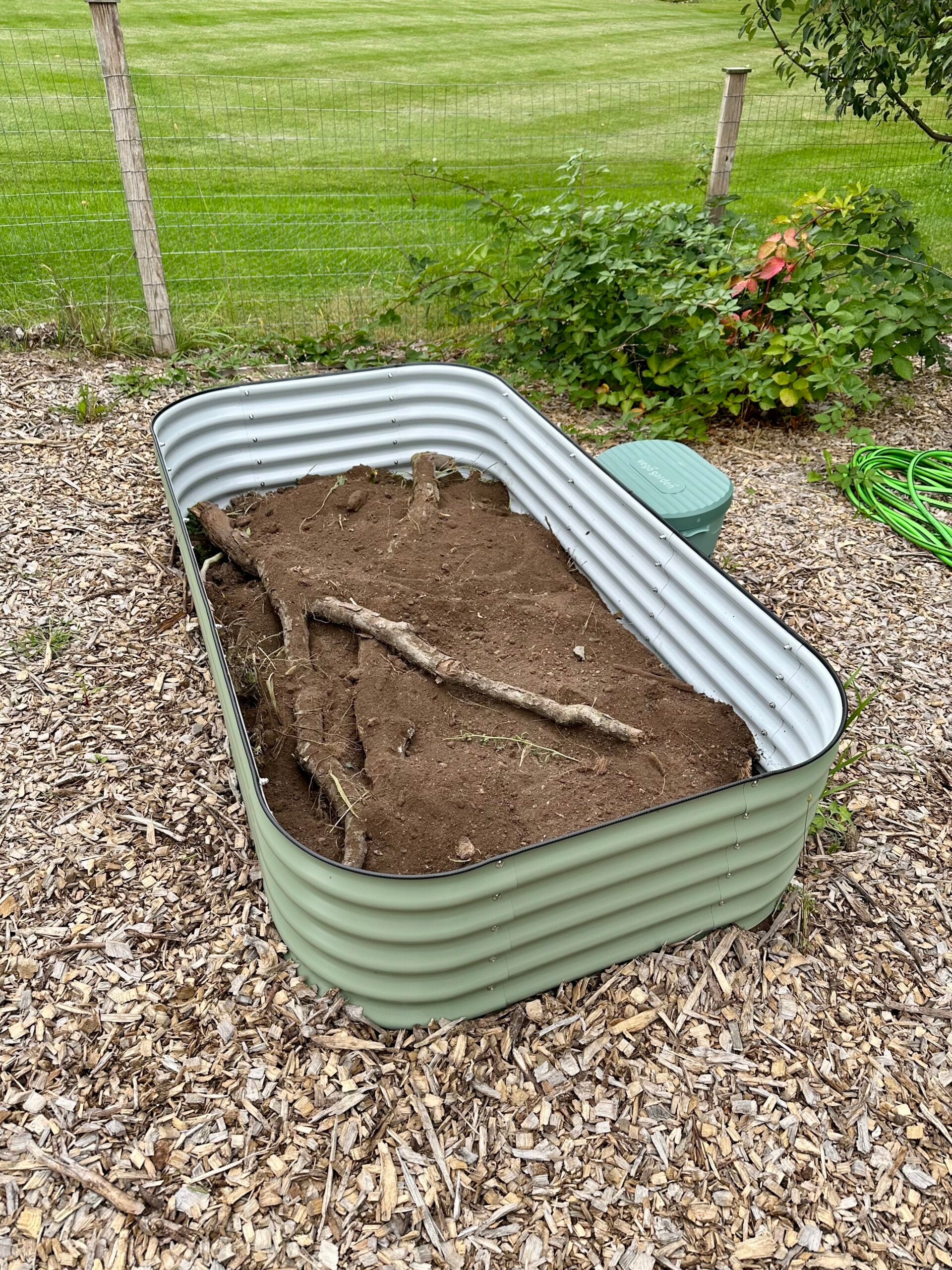 Filling a raised bed with logs and soil